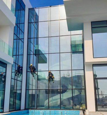 A team from Liverpool Services cleaning a large window using a rope-access system